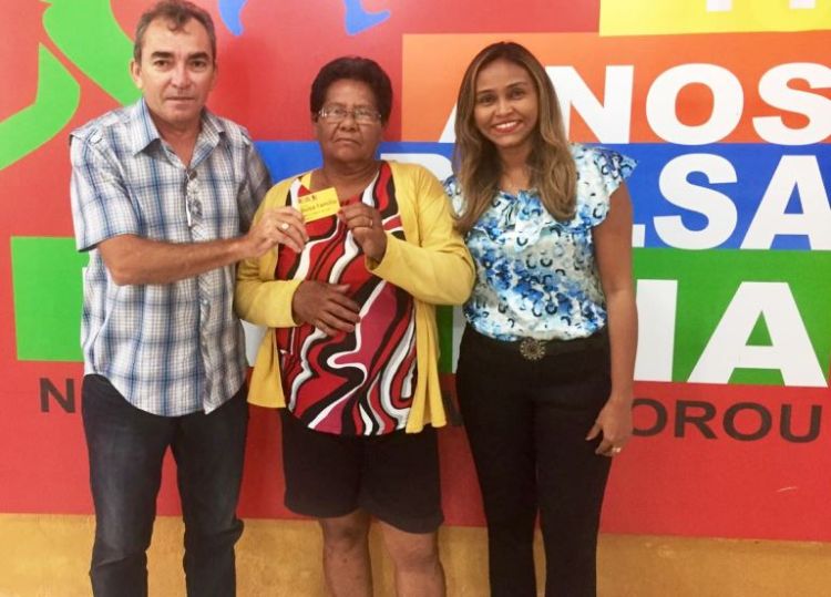 Dona Remédios entrega o cartão ao coordenador do Bolsa Família, Miguel Ribeiro e à Secretária Nilsana Gomes.